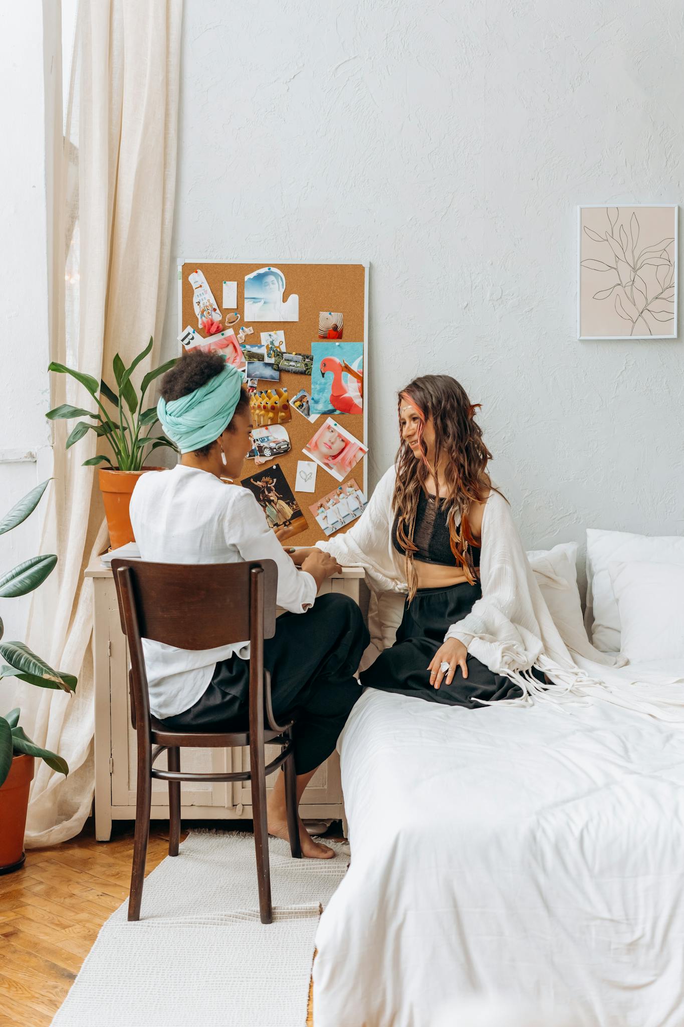 Two women sitting in a cozy bedroom having a heartfelt conversation, promoting wellness and connection.
