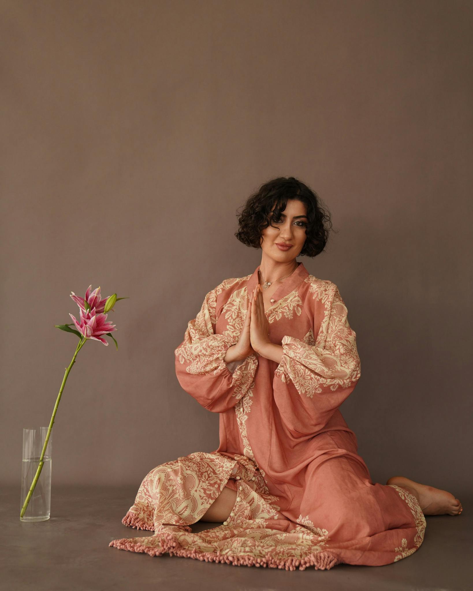 Woman meditating in embroidered gown with a pink lily, Las Vegas setting.